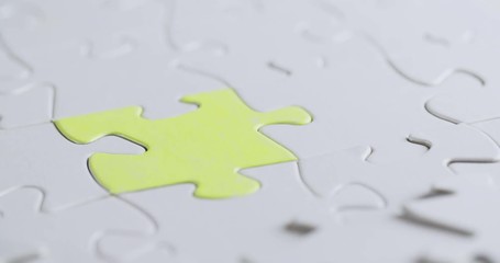 Closeup shot of a female hand completing a jigsaw puzzle with a green colored piece. Chroma key compositing possible.