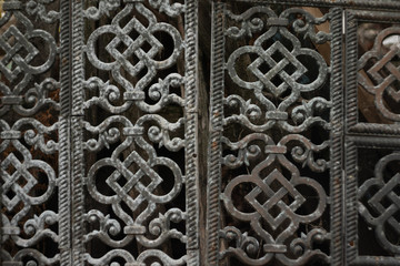 An old metal grille. Composed of patterned openwork plates with oriental ornament. The gray plaque of antiquity