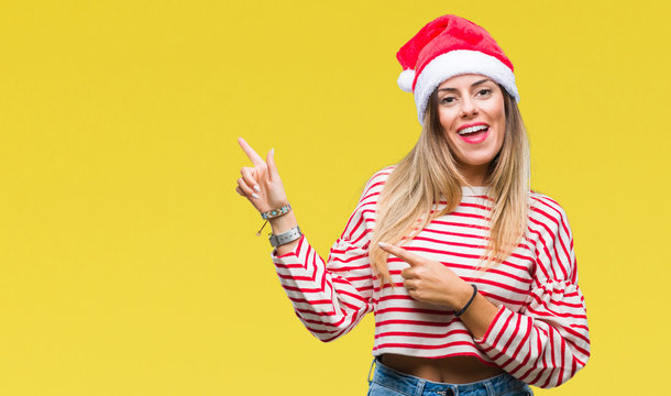 Young beautiful woman wearing christmas hat over isolated background smiling and looking at the camera pointing with two hands and fingers to the side.