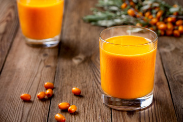 Two glasses of fresh pressed sea buckthorn juice on a wooden table. The concept of a healthy lifestyle.
