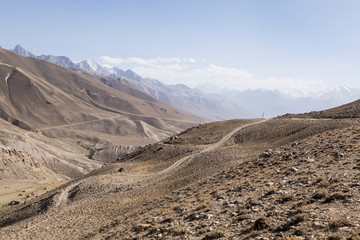 Pamir Highway in the desert landscape of the Pamir Mountains in Tajikistan. Afghanistan is on the left