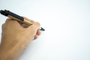 Hand holding ballpoint pen pointing on white paper. Selective focus.