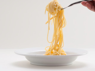 hand holding roll pasta spaghetti with a fork and bish