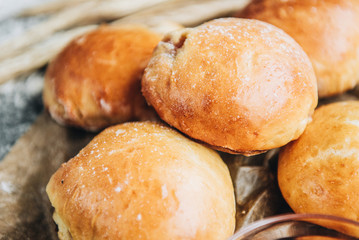Fresh baked yeast buns filled with apple jam on gray background with flour.