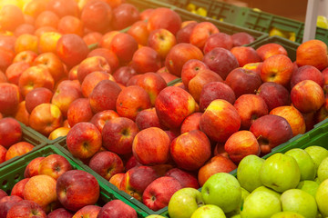Beautiful, ripe, fresh fruits in the store: green, yellow, red apples, laid out in rows on the shelves, attracting the attention of buyers and offering a large assortment. Paradise for a vegetarian.