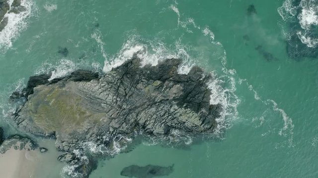 Aerial descending shot over rocky coastline Sango sands. Waves crashing against rocks.