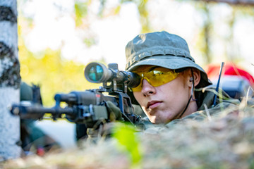 Sniper armed with large caliber, sniper rifle, shooting enemy targets on range from shelter,...
