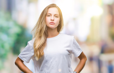 Fototapeta premium Young beautiful blonde woman wearing casual white t-shirt over isolated background with serious expression on face. Simple and natural looking at the camera.