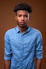 Young handsome African man against brown background