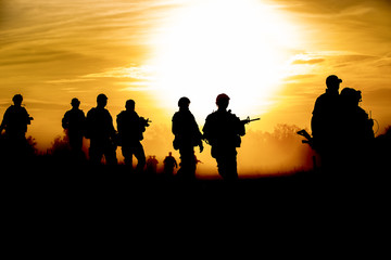 silhouette action soldiers walking hold weapons the background is smoke and sunset and white...