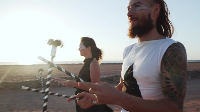 Man and girl make flaverstik performance in desert at sunset shaky footage