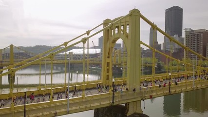 Aerial high-angle follow shot of runners crossing bridge, Pittsburgh Marathon.
