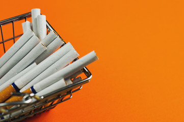 Full market basket of cigarettes with filter on orange background with copy space for your text or logo. Business concept