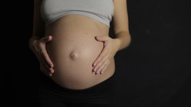 pregnant women caressing her belly slow motion dark backround