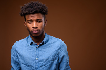 Young handsome African man against brown background