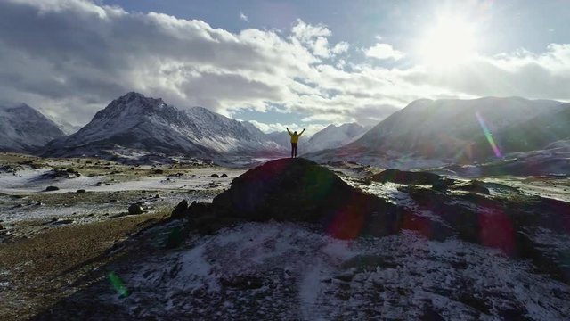 Mountaineer reaches the top of a snowy mountain in a sunny winter day.