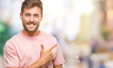 Fototapeta premium Young handsome man over isolated background cheerful with a smile of face pointing with hand and finger up to the side with happy and natural expression on face looking at the camera.