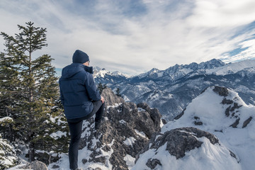 Fototapeta premium One guy with glasses looks at the beautiful panorama of the mountains covered with snow