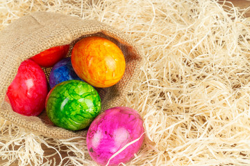 Fototapeta na wymiar Colorful Easter eggs in Easter basket, straw background
