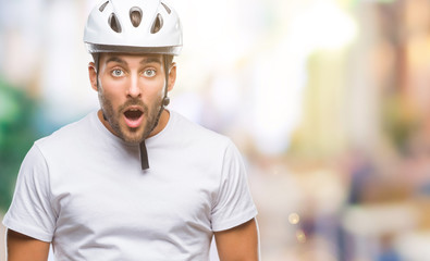 Young handsome man wearing cyclist safety helmet over isolated background afraid and shocked with...