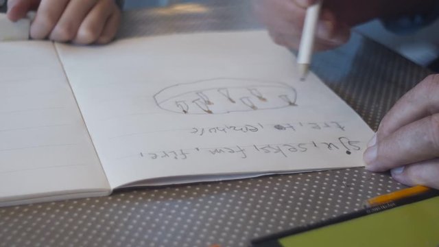 Boy learning to read and write from book.