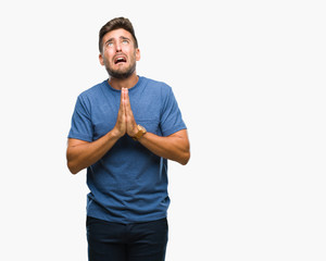 Young handsome man over isolated background begging and praying with hands together with hope...