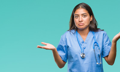 Young arab doctor surgeon woman over isolated background clueless and confused expression with arms...