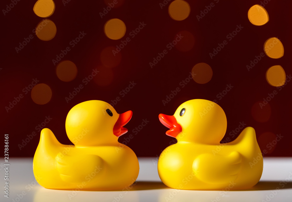 Wall mural rubber duck toys on a shiny light dark red background