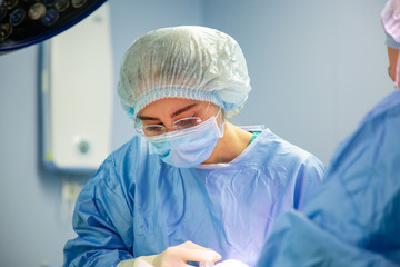 Female Doctor in Surgery Operating Hospital Room. Surgeon medic in protective work wear gloves, mask and cap