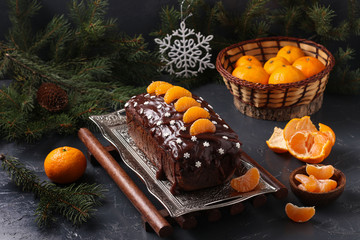 Cupcake with tangerines, covered with chocolate glaze is located on the New Year's or Christmas background