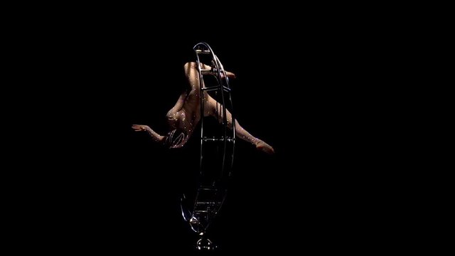 Acrobatic hangs upside down in a twine on a rotating moon. Black background. Slow motion
