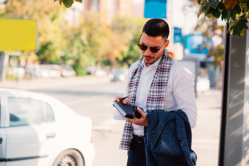 Handsome businessman is in the city, talking and walking on the street, holding notebook in his hands.