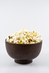 Popcorn in wooden bowl isolated on white background. Selective focus.