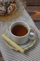 A Cup of fragrant tea and delicious sweet cookies on a wooden background.