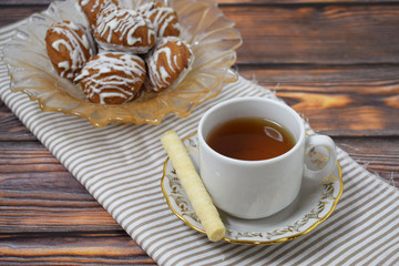 A Cup of fragrant tea and delicious sweet cookies on a wooden background.