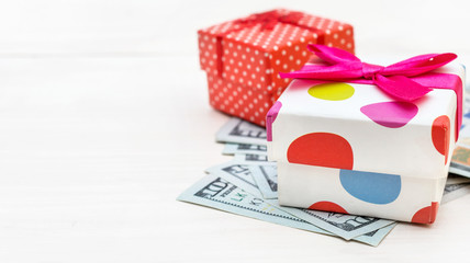 Fototapeta premium Gift box with dollar bills on white wooden background. Space for text.