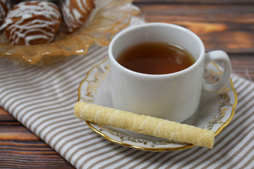 A Cup of fragrant tea and delicious sweet cookies on a wooden background.