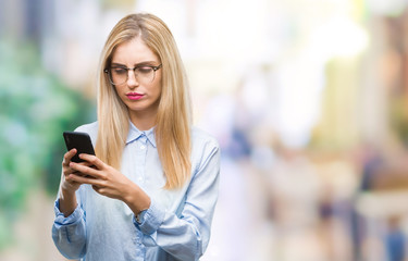Young beautiful blonde business woman using smartphone over isolated background with a confident expression on smart face thinking serious