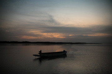 mała łodź rybacka na spokojnym jeziorze po zachodzie słońca w afryce