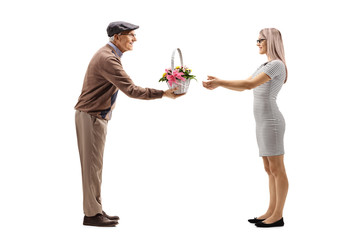 Senior man giving a basket with flowers to a young woman