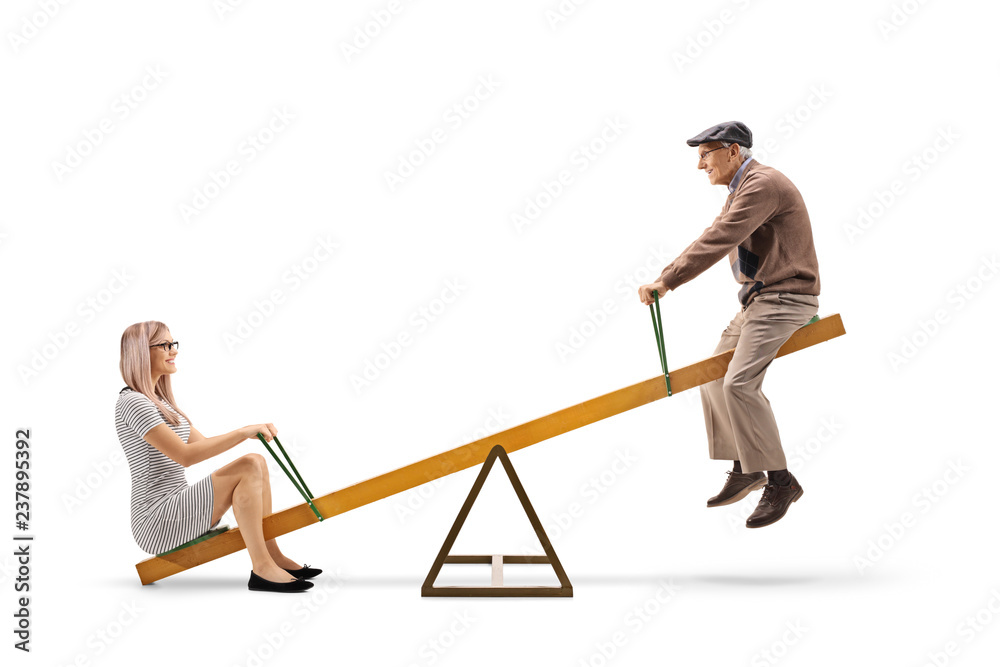 Wall mural Young woman and a senior man playing on a seesaw