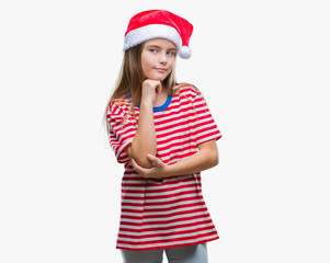 Young beautiful girl wearing christmas hat over isolated background with hand on chin thinking about question, pensive expression. Smiling with thoughtful face. Doubt concept.