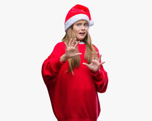 Young beautiful girl wearing christmas hat over isolated background afraid and terrified with fear expression stop gesture with hands, shouting in shock. Panic concept.