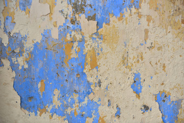 Beautiful colors layers of an outdoor plaster wall showing several times of wall repairing. Each color showing a new layer had been added to hide the old one below from time to time. 
