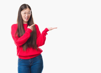 Young Chinese woman over isolated background wearing glasses amazed and smiling to the camera while presenting with hand and pointing with finger.