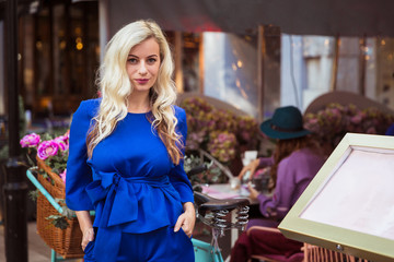 The beautiful, elegant young woman standing in cafe outdoor