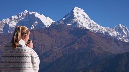 Young Caucasian Woman Drinking Hot Tea with View of Annapurna Mountain in Nepal. Active Female Tourism. Trekking in the Himalayas