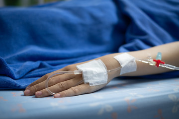Woman patient receiving intravenous fluid through IV line in the room after surgery at the hospital.