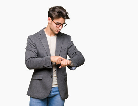 Young business man wearing glasses over isolated background Checking the time on wrist watch, relaxed and confident