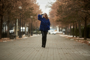 Fototapeta premium The girl walks through the city in a fur coat
